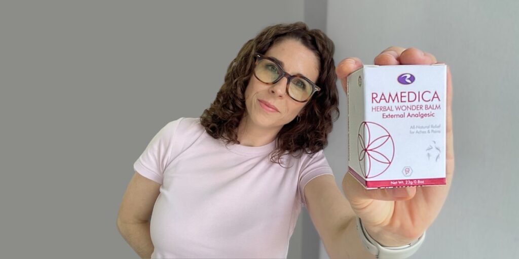 Ramedica Herbal Wonder Balm in hand surrounded by natural healing elements