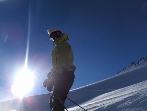 Jaime smiling in ski gear with bright alpine sun behind her in the Bugaboos.