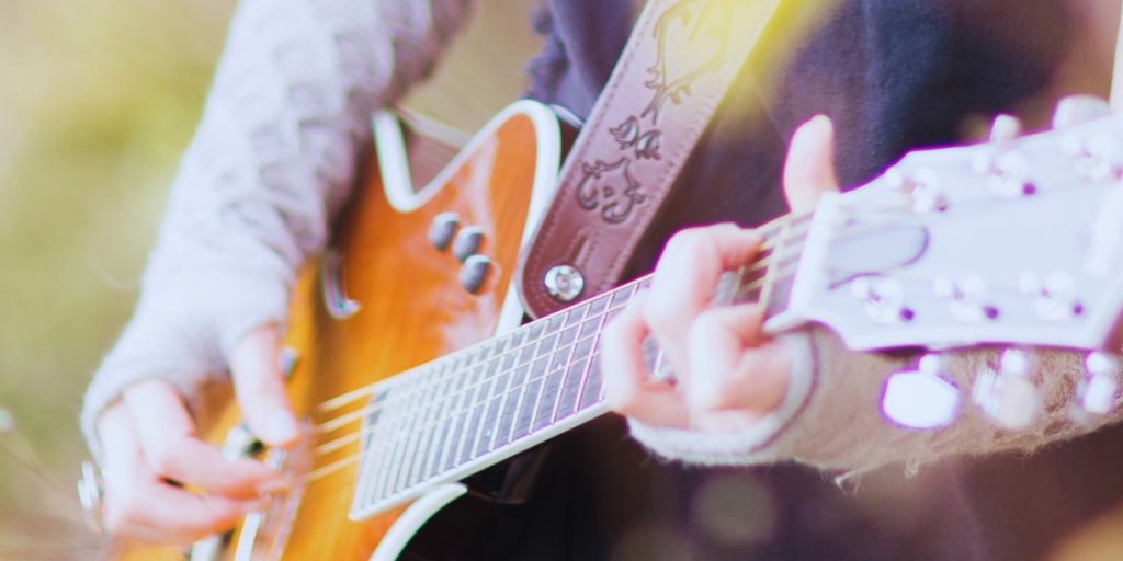 Woman playing guitar, exploring music and healing through personal loss