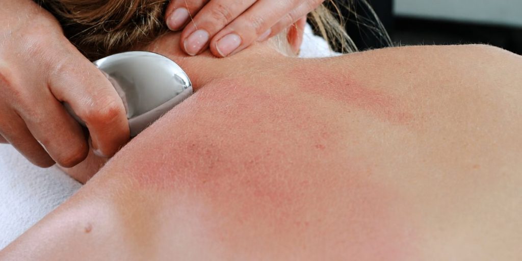 Gua Sha tool being used on the neck and shoulder area to support recurring muscle tension relief