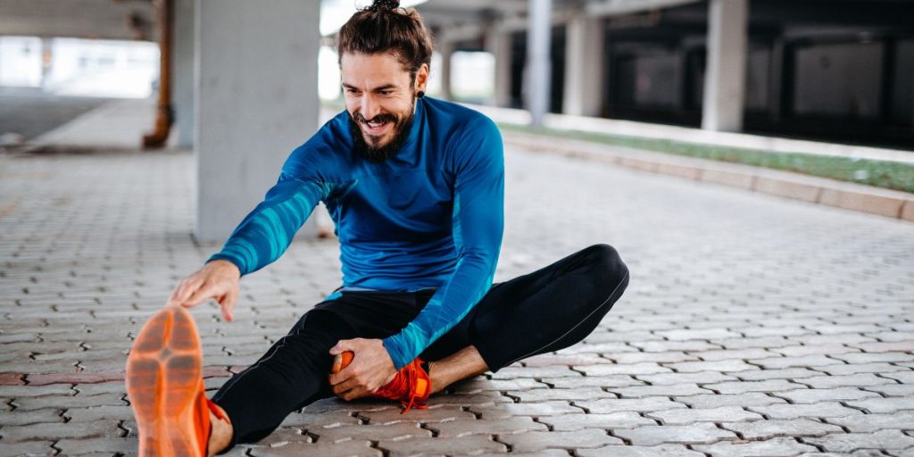 Man stretching tight leg muscles outdoors